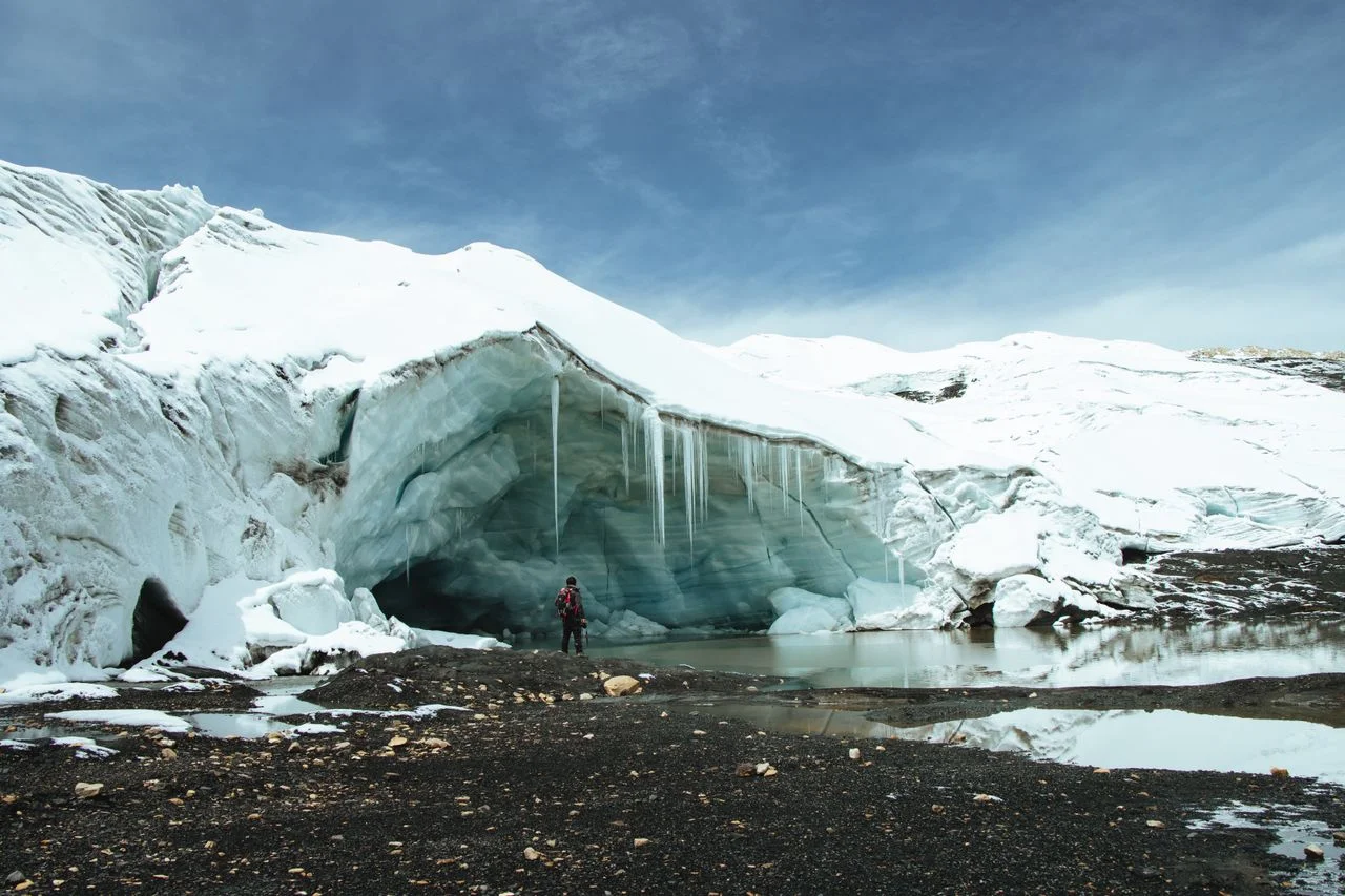 Viajero frente a una gran cueva de hielo en el glaciar Quelccaya, Cusco