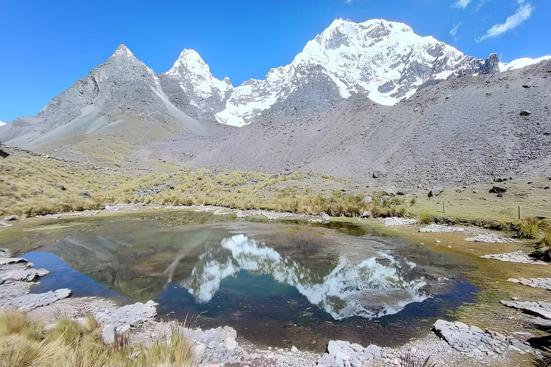High-altitude lagoon reflecting the snow-covered Ausangate mountains along the 7 Lakes hiking route.