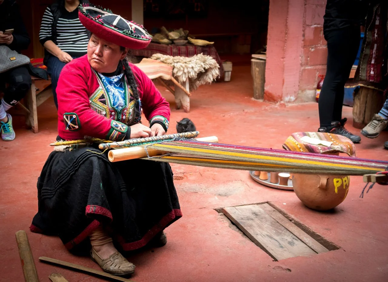 Andean woman demonstrating traditional weaving techniques in Chinchero during a Sacred Valley tour.