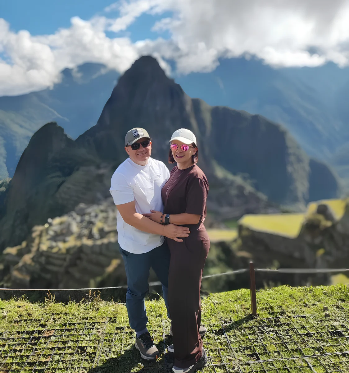 Couple posing at a Machu Picchu viewpoint with the citadel and Andean mountains in the background