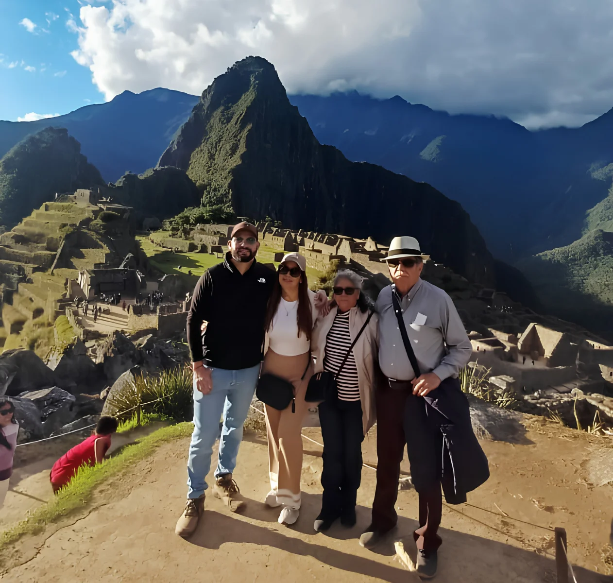 Group of travelers posing in front of Machu Picchu citadel surrounded by mountains