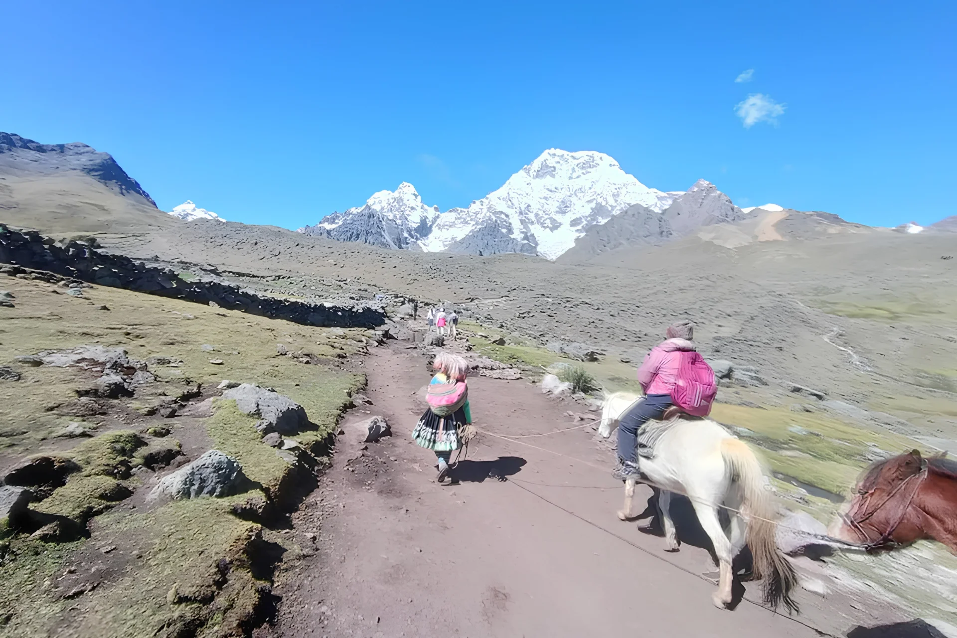 Traveler riding a horse along the high-altitude trail of the Ausangate 7 Lakes route near Pacchanta.
