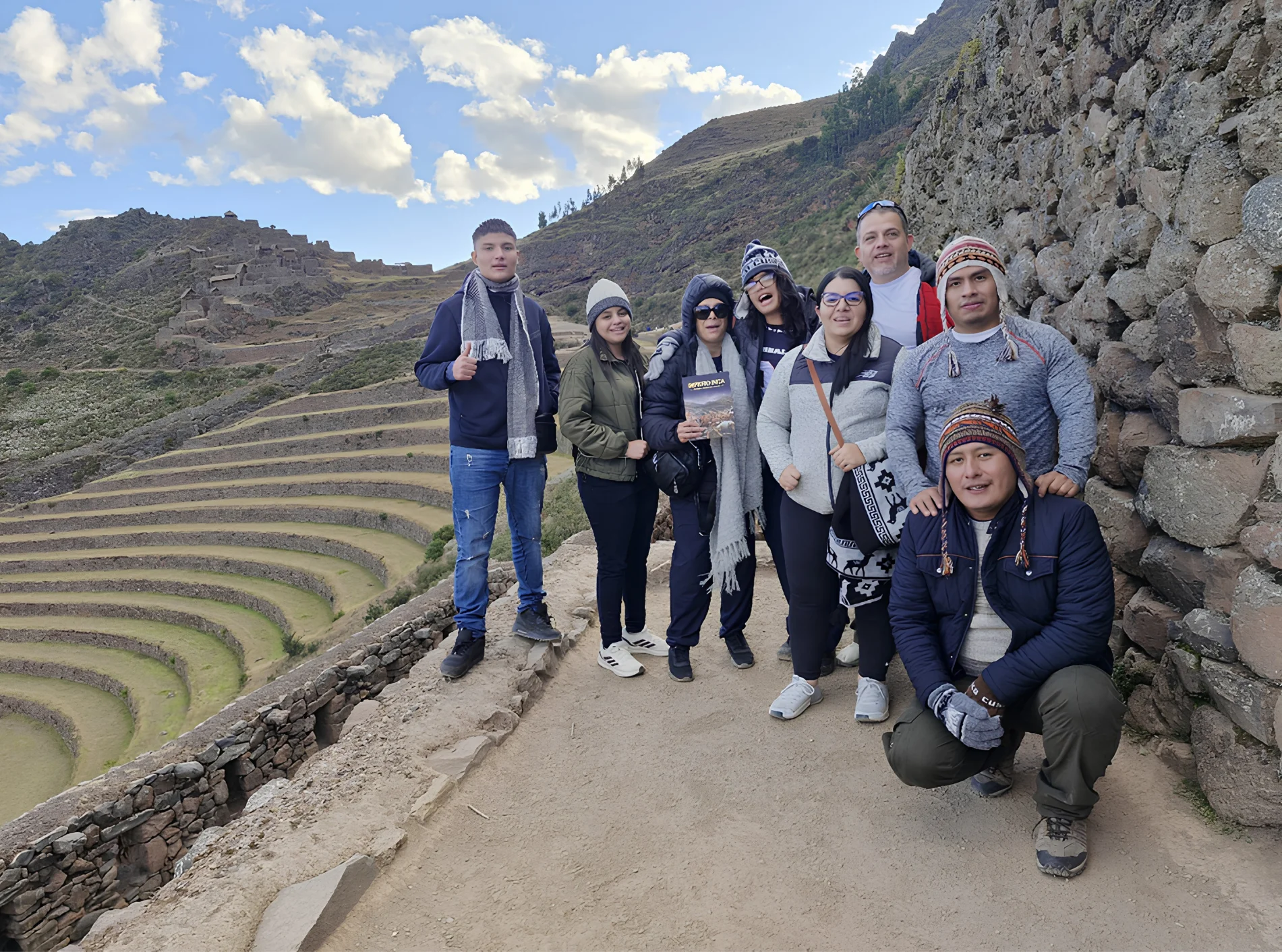 Travelers beside Inca terraces at the Pisac archaeological site during a Sacred Valley tour from Cusco.