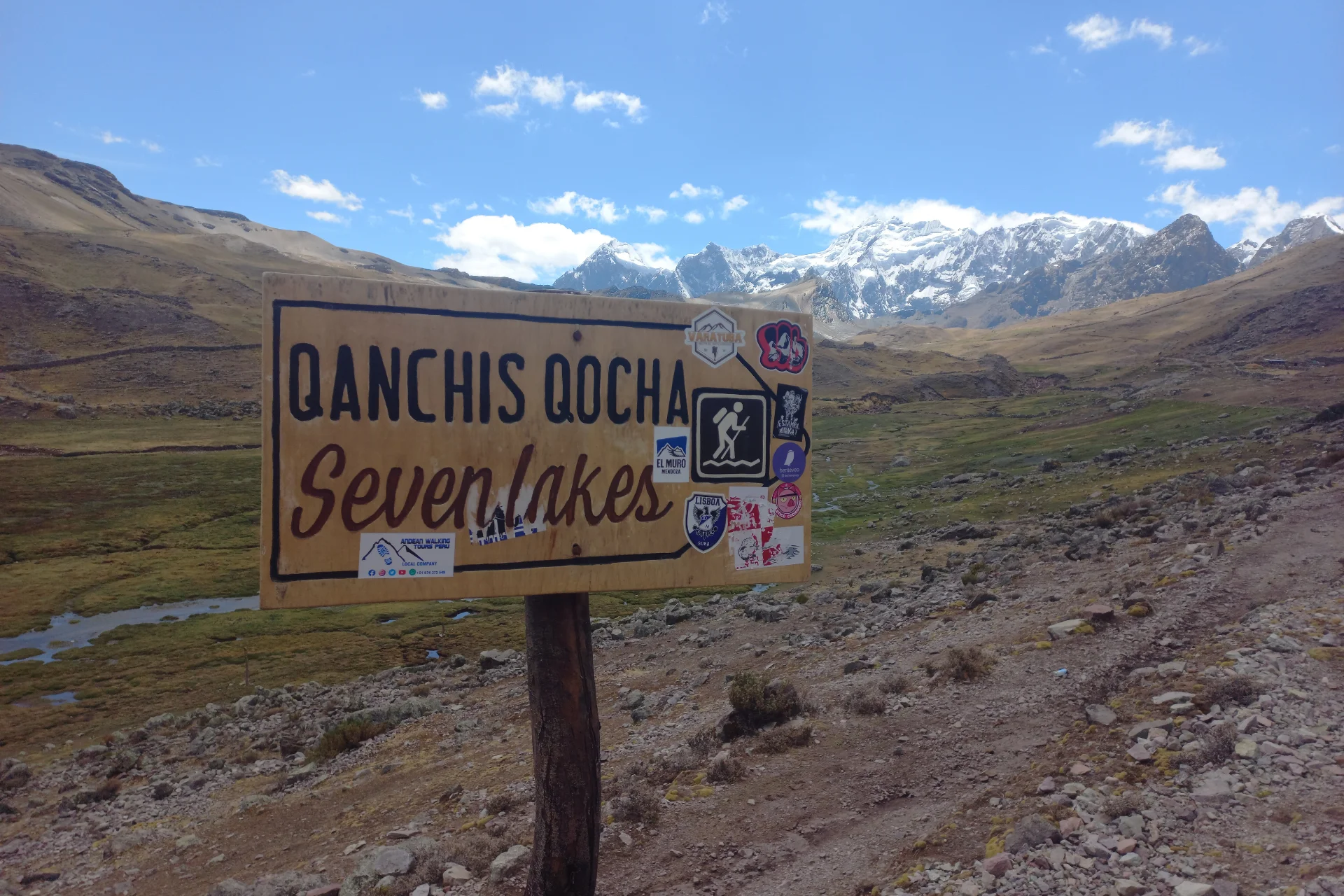 Qanchis Qocha Seven Lakes sign with the Ausangate mountain landscape in the background during the hike from Pacchanta.