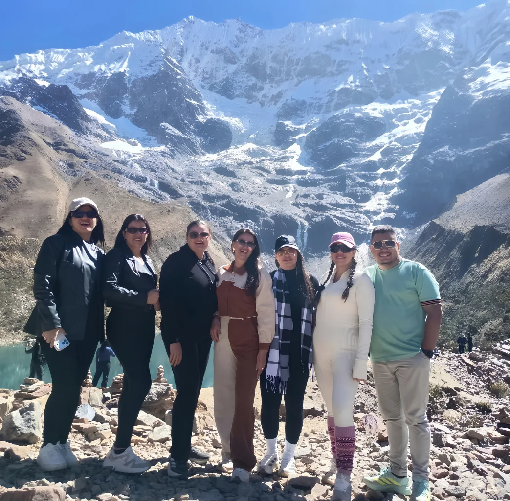 Travelers at Humantay Lake beneath snow-covered mountains during the Salkantay Trek 4 Days to Machu Picchu.