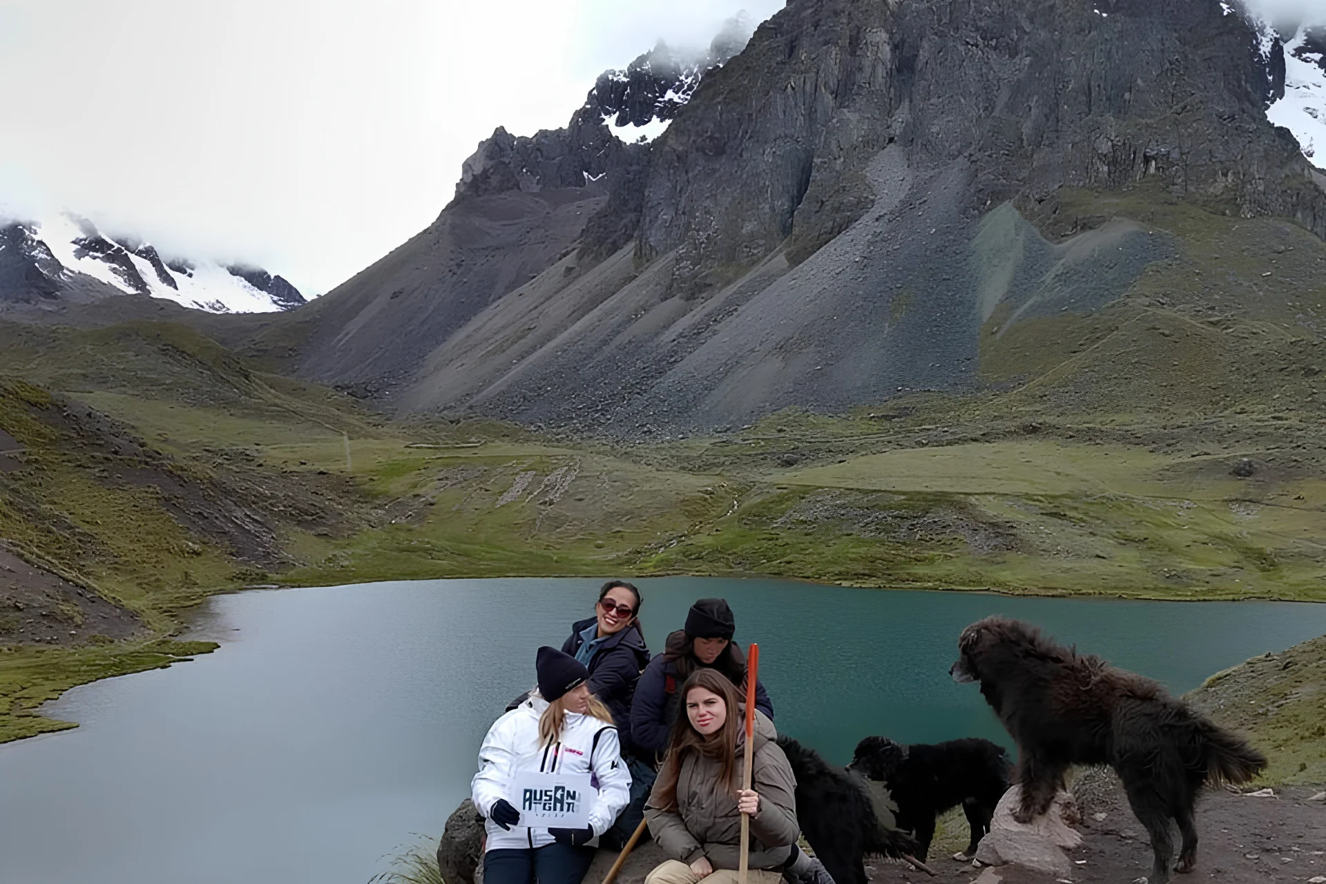 Travelers resting beside a turquoise mountain lagoon during the Ausangate 7 Lakes hike near Cusco.