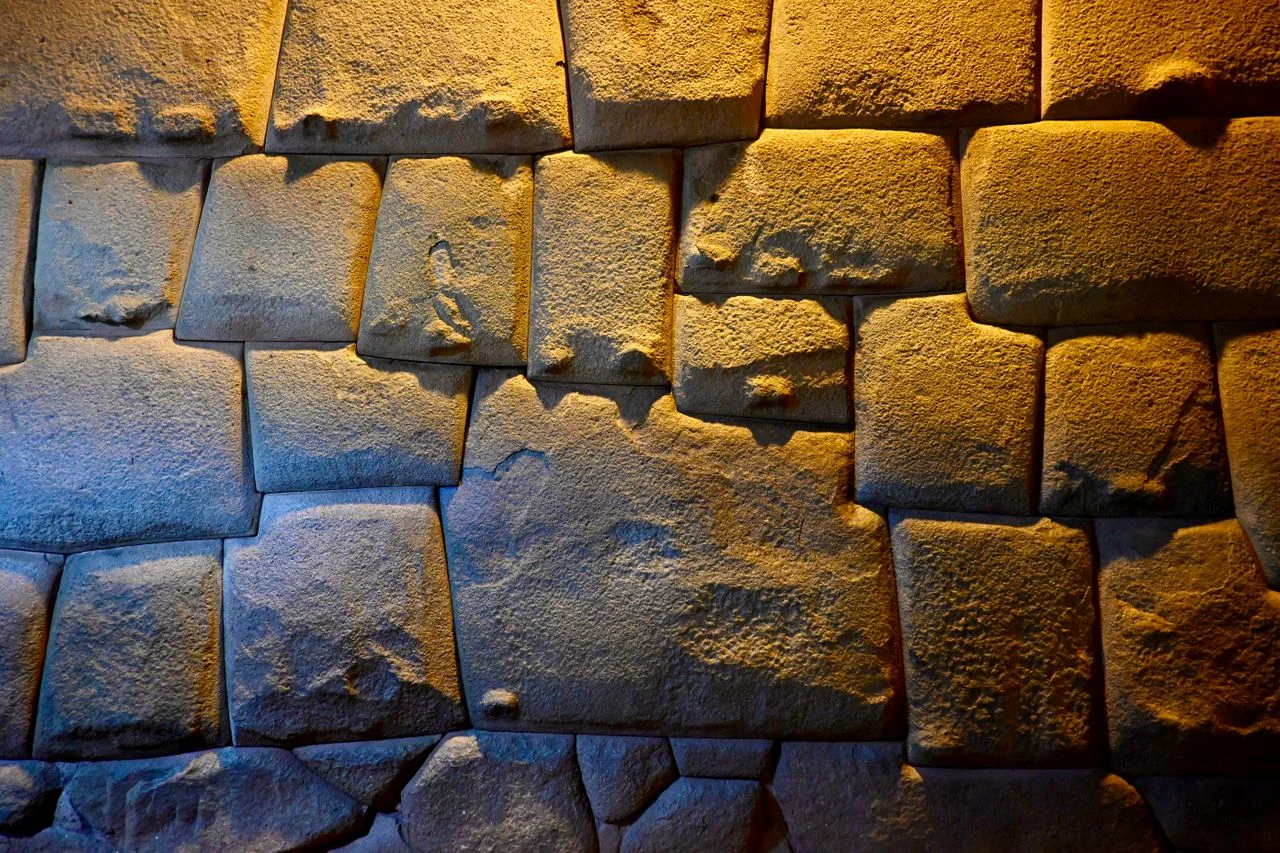 Visitors beside the famous Twelve-Angled Stone and Inca wall in the historic center of Cusco.