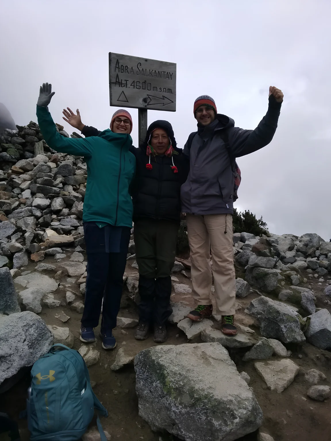 Travelers reaching a high mountain pass surrounded by rocky Andean scenery on the Salkantay Trek.