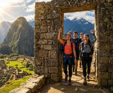 Happy hikers arriving through the Sun Gate with a scenic view of Machu Picchu in the background | Inca Culture Travel