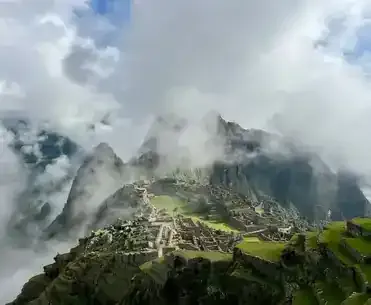 Panoramic view of the Machu Picchu inca citadel partially covered by morning mist and clouds in Cusco | Inca Culture Travel