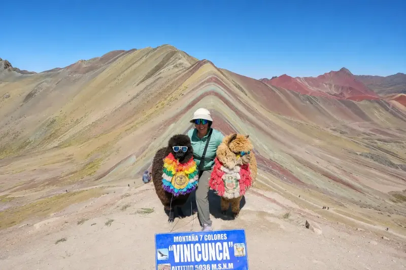 Tourists posing next to the Rainbow Mountain Vinicunca sign in Peru | Inca Culture Travel 