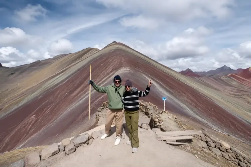 Single hiker raising arms at the summit of Rainbow Mountain, Peru | Inca Culture Travel 