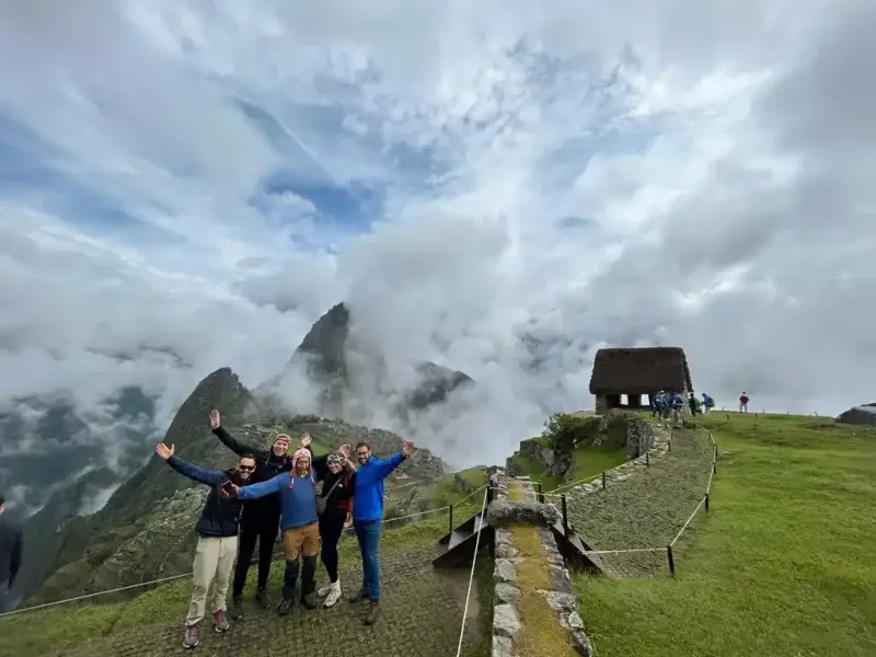 Grupo de excursionistas celebrando con los brazos abiertos en el camino de piedra del Camino Inca Clásico a Machu Picchu | Inca Culture Travel
