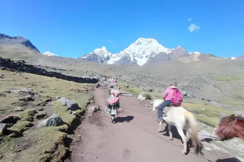 Traveler riding a horse along the high-altitude trail of the Ausangate 7 Lakes route near Pacchanta.