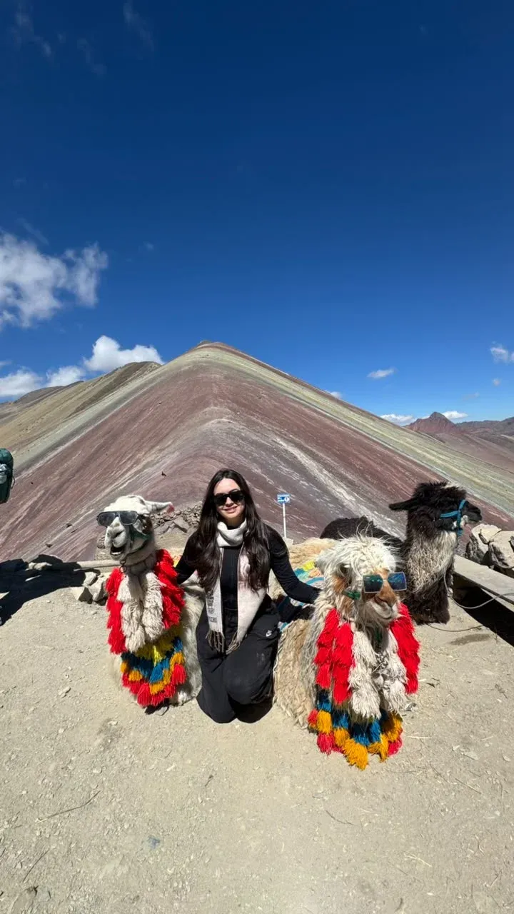 Traveler with alpacas in front of Rainbow Mountain in Cusco