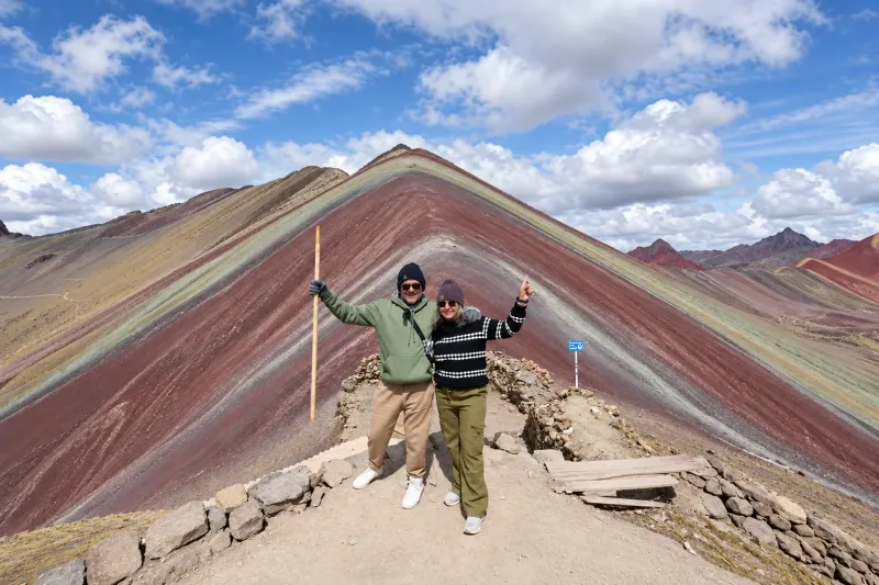 Hiker raising their arms at the summit of Rainbow Mountain in Peru