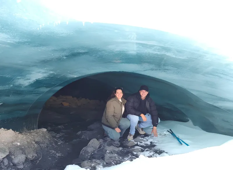Dos viajeros en la entrada de una formación de hielo azul del glaciar Quelccaya