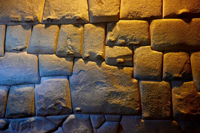 Visitors beside the famous Twelve-Angled Stone and Inca wall in the historic center of Cusco.