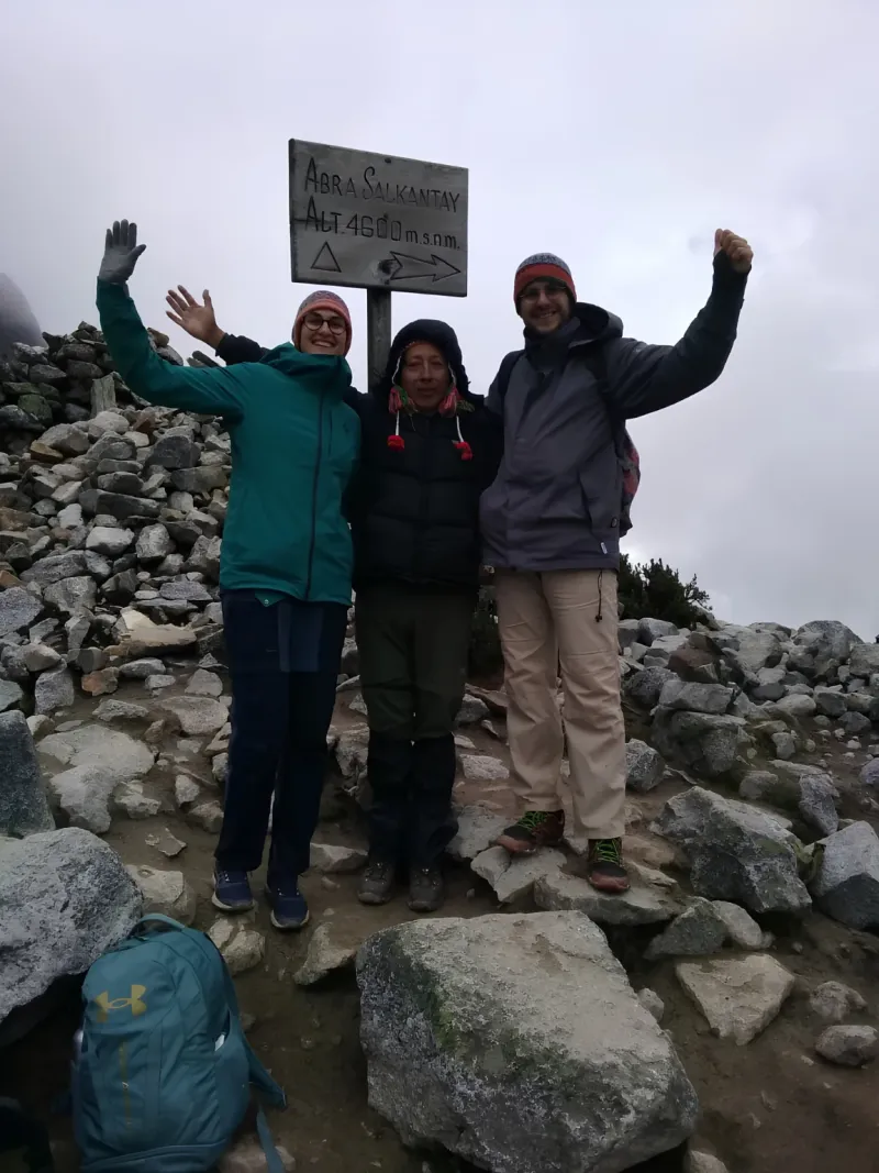 Travelers reaching a high mountain pass surrounded by rocky Andean scenery on the Salkantay Trek.
