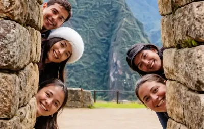 Group of friends smiling behind an Inca stone wall at Machu Picchu citadel