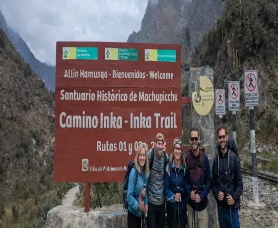 Tourists at the entrance to the Inca Trail to Machu Picchu, next to the official Inca Trail sign in the Peruvian Andes